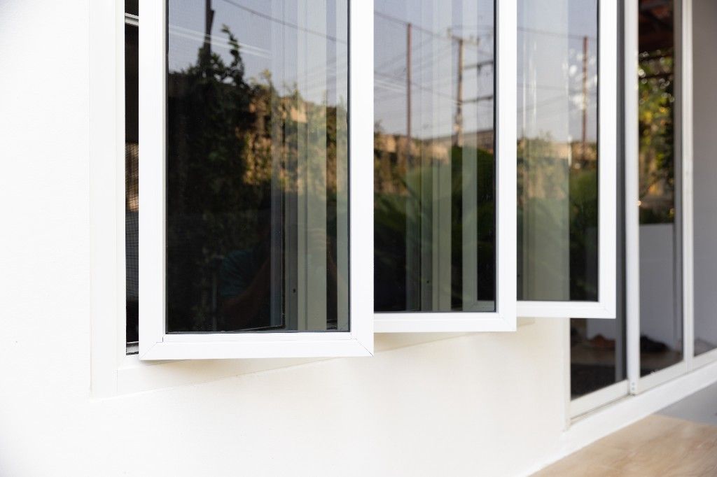 Three modern white-framed awning windows on an exterior wall
